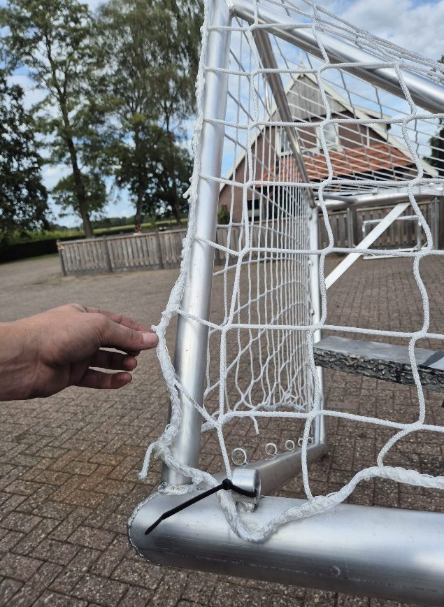 Het net hangt in het doel, met het dikke touw over de netbeugel