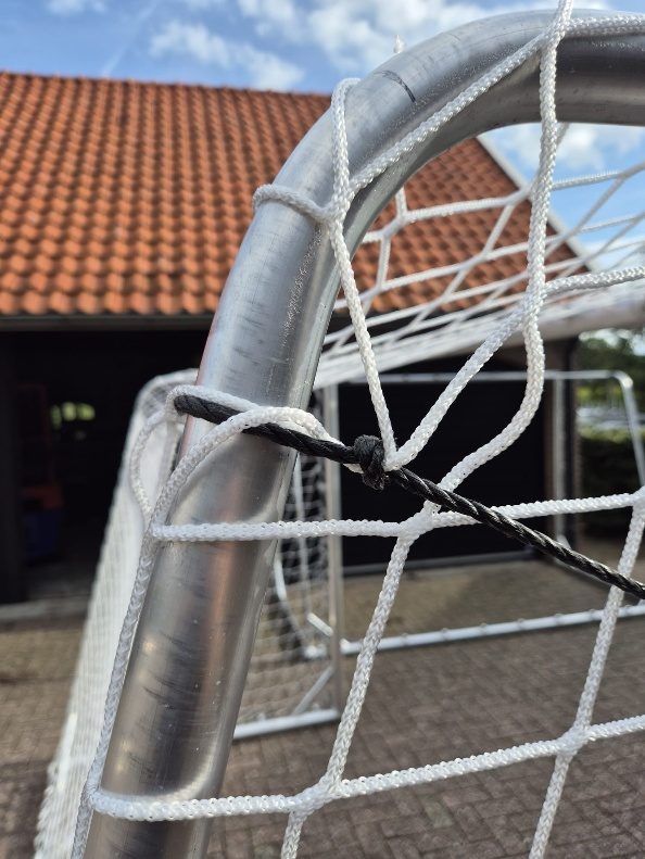 Het zwarte touw loopt langs de netbeugel van het doel